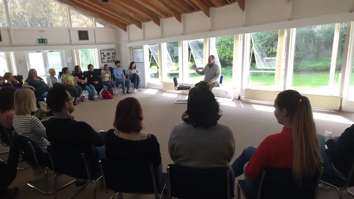 Robert guiding a group meditation session in a light-filled hall