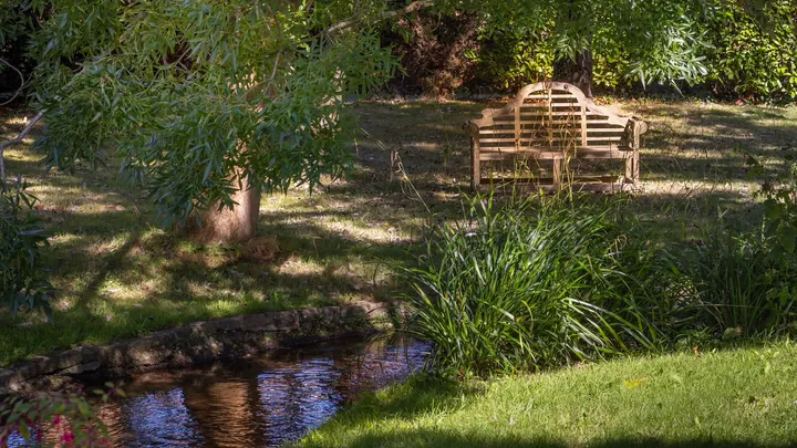 A quiet garden bench beside a stream at one of our retreat venues